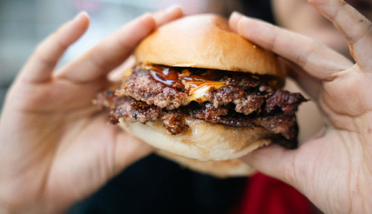Person eating smash cheese burger made on a Blackstone BBQ
